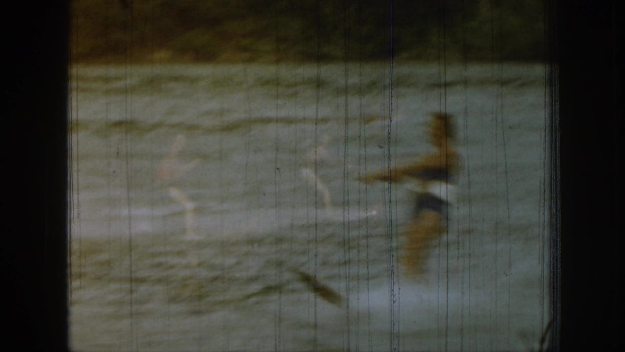 Person in dark swimwear crossing lake water with spray behind them.