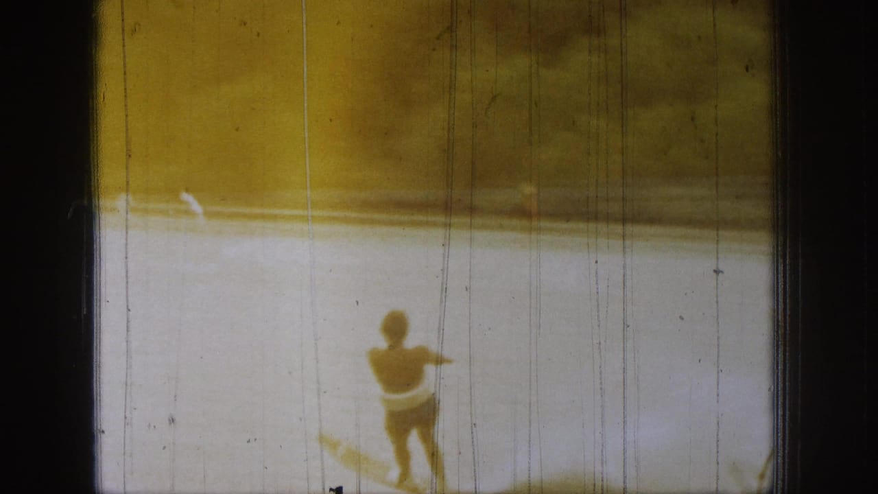 A small figure appears against bright lake water in 1961 Michigan footage, with a wake line and yellowed 8mm exposure.