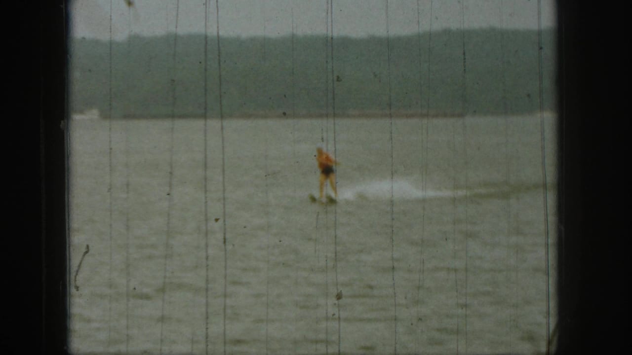Water-skier gliding across open water with a tree-lined horizon.
