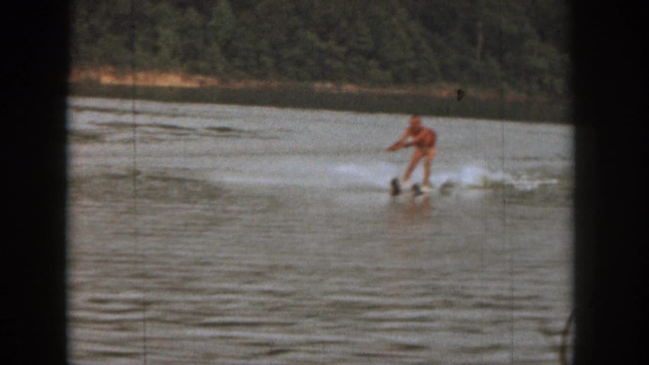Water skier gliding across open water with spray behind them.