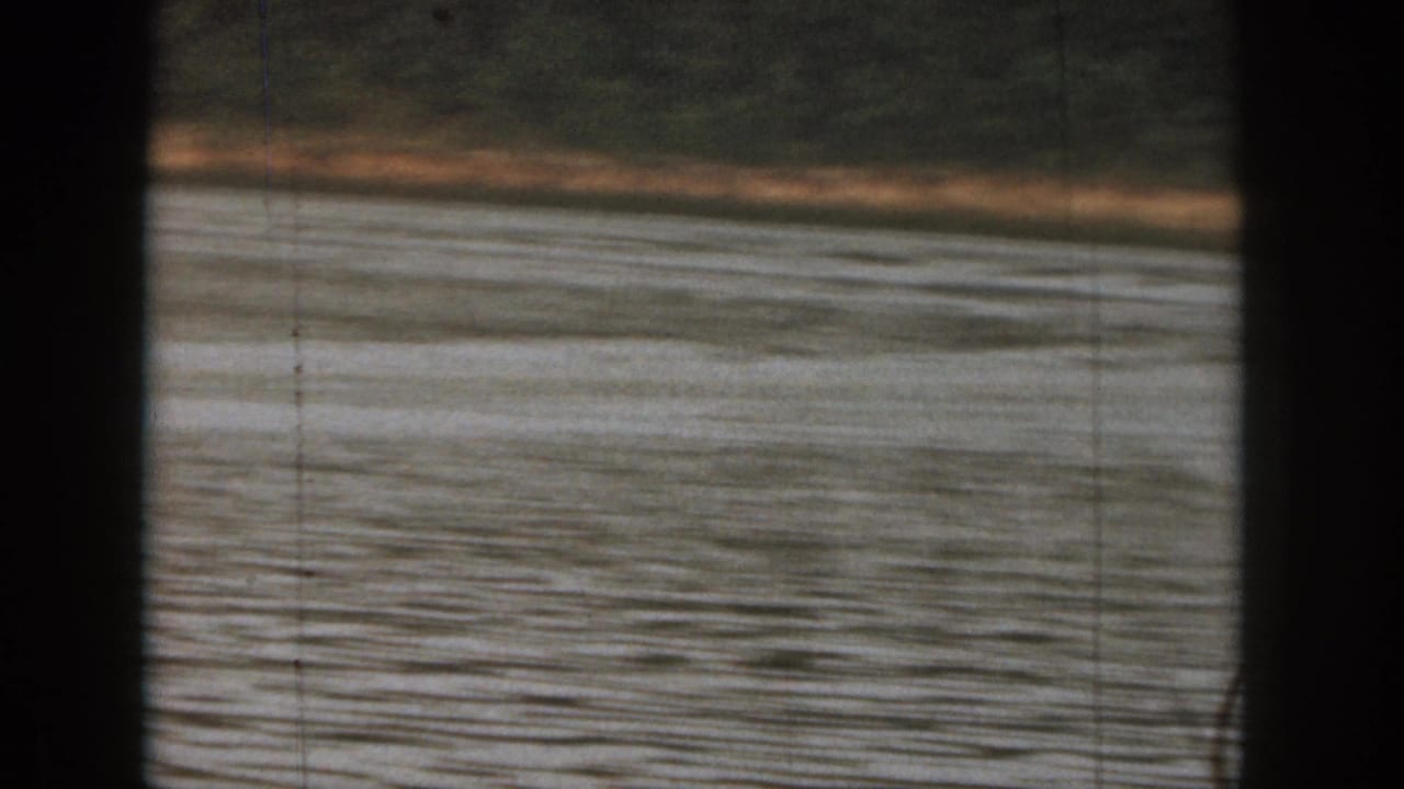 1961 Michigan 8mm frame showing lake water and a distant wooded shore after the skier has moved out of the visible area.