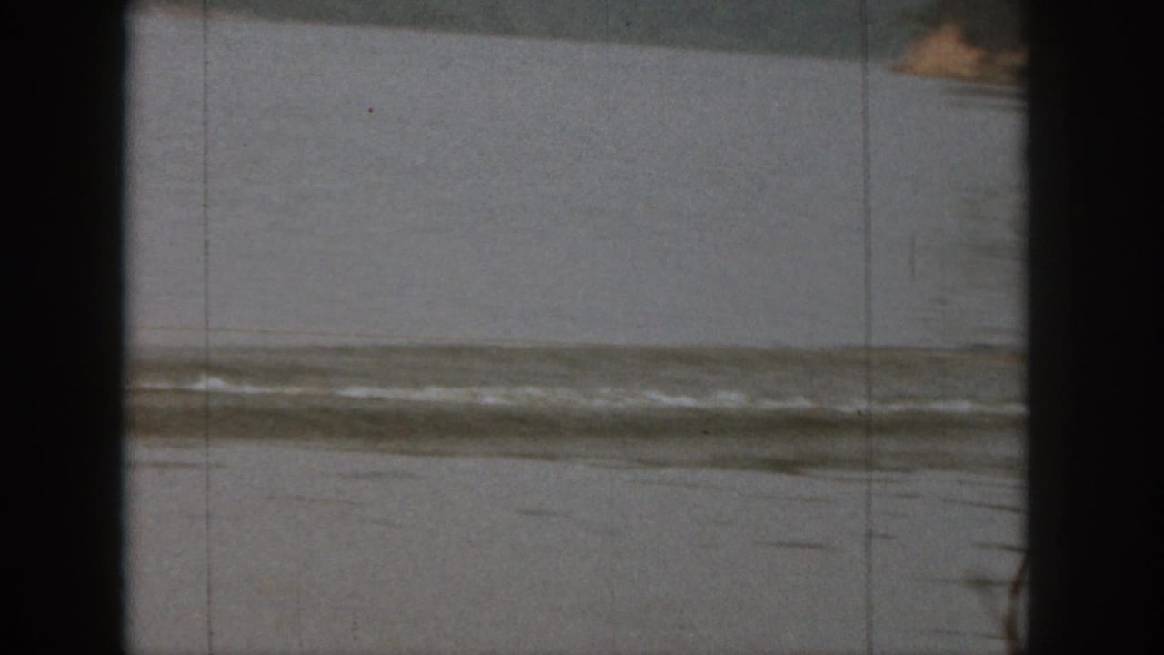 Michigan lake scene from 1961 home-movie footage, showing calm water, distant shoreline, and visible 8mm film frame edges.