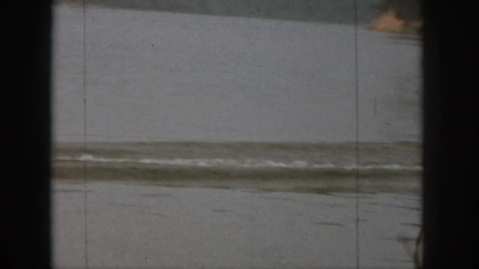 Michigan lake scene from 1961 home-movie footage, showing calm water, distant shoreline, and visible 8mm film frame edges.