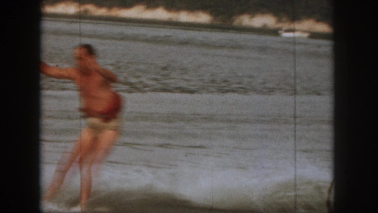 Adult man in swim trunks appears off balance in the water during a 1961 Michigan lake recreation scene.