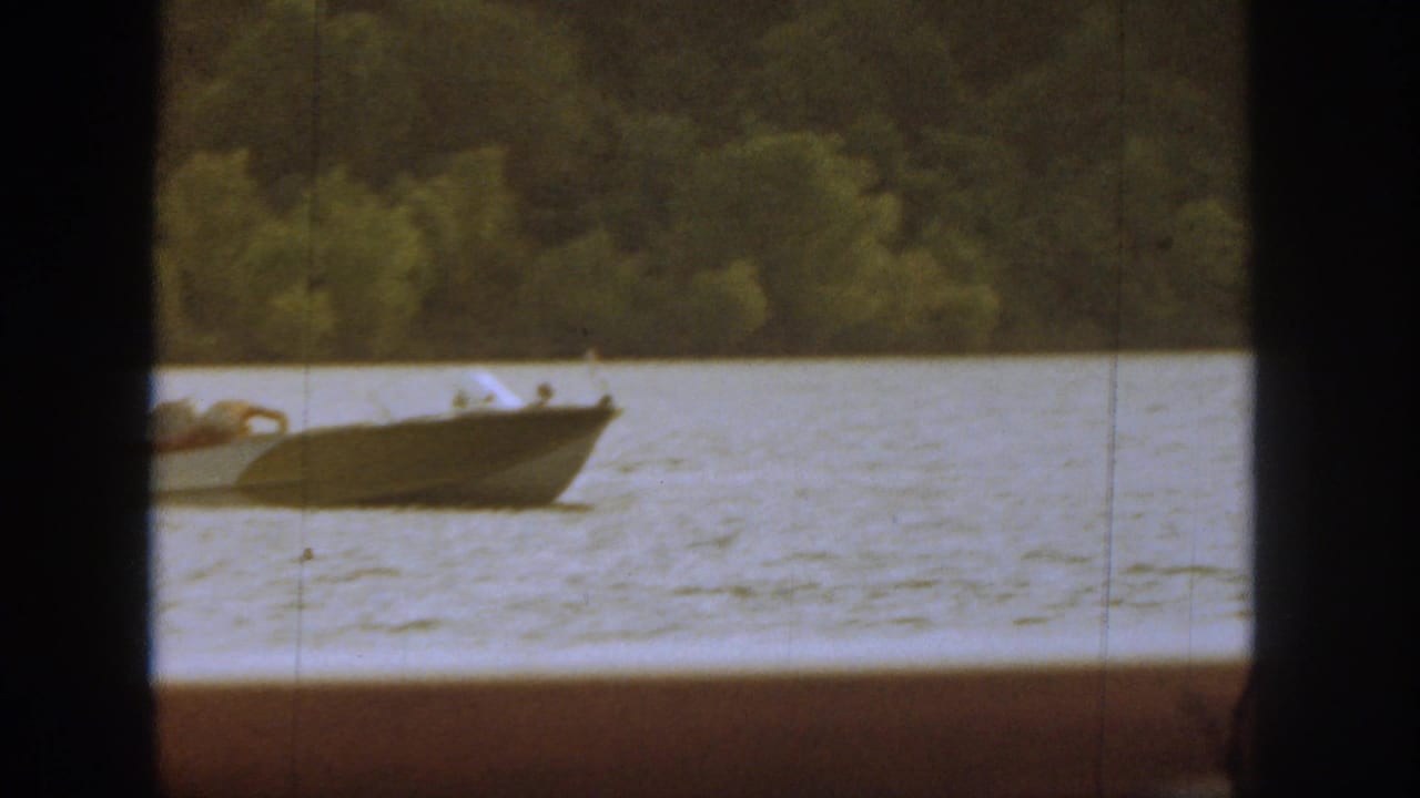 Motorboat passing on the river, partly obscured by a central dark window bar.