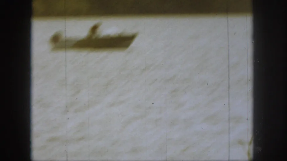 Distant motorboat appears blurred on bright river water in a 1961 Michigan home-movie frame with dark window edges.