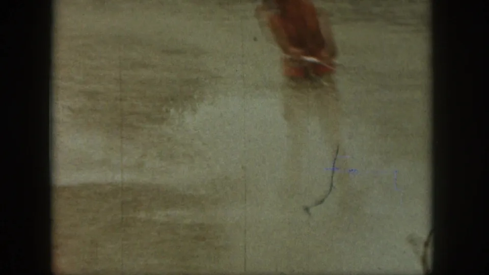 Close 8mm view of a person’s lower legs moving through shallow Michigan lake water, with spray and film scratches visible.