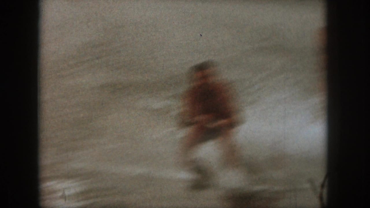 A blurred man water skiing across rough lake water.