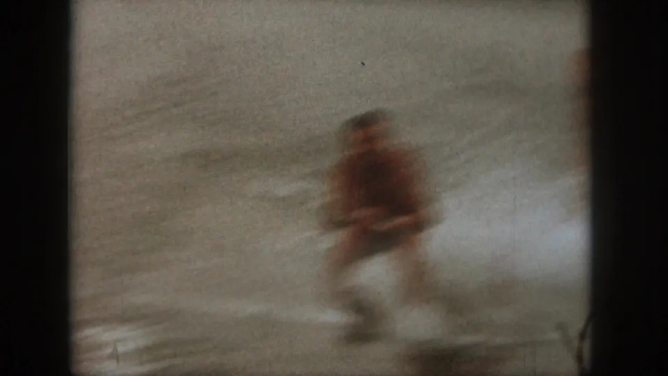 A man appears to water ski across a Michigan lake in soft, motion-blurred 1961 8mm home-movie footage.