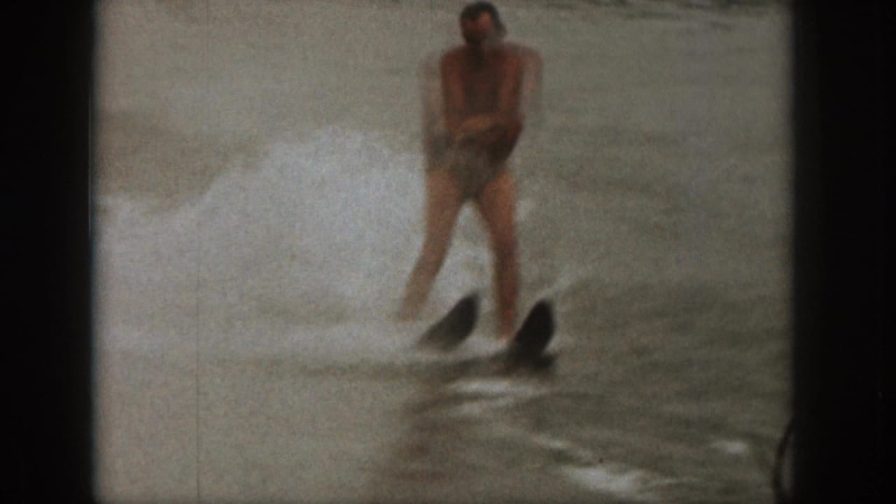 Water skier leans back while holding a tow rope over choppy lake water.