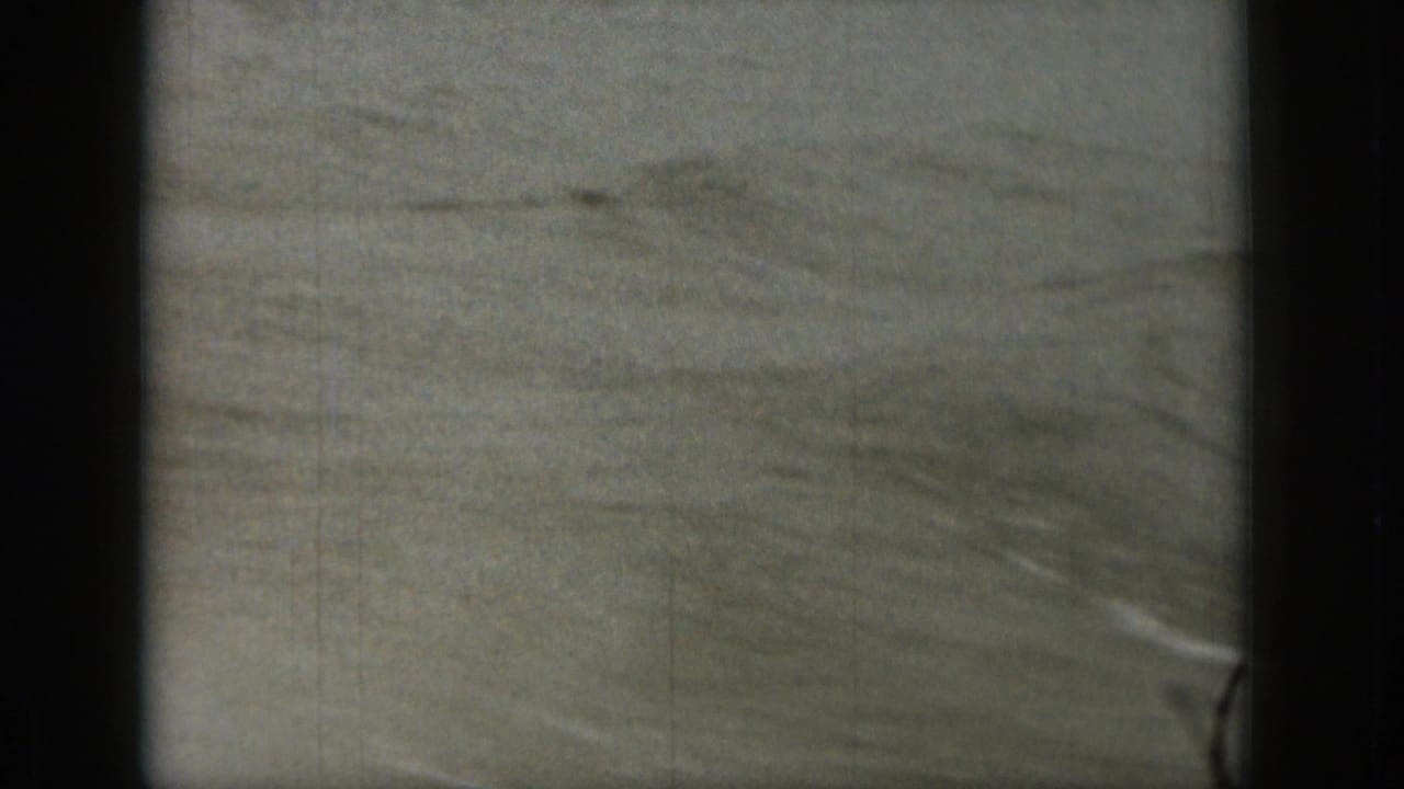 Soft, grainy view of rippling water with dark film borders.