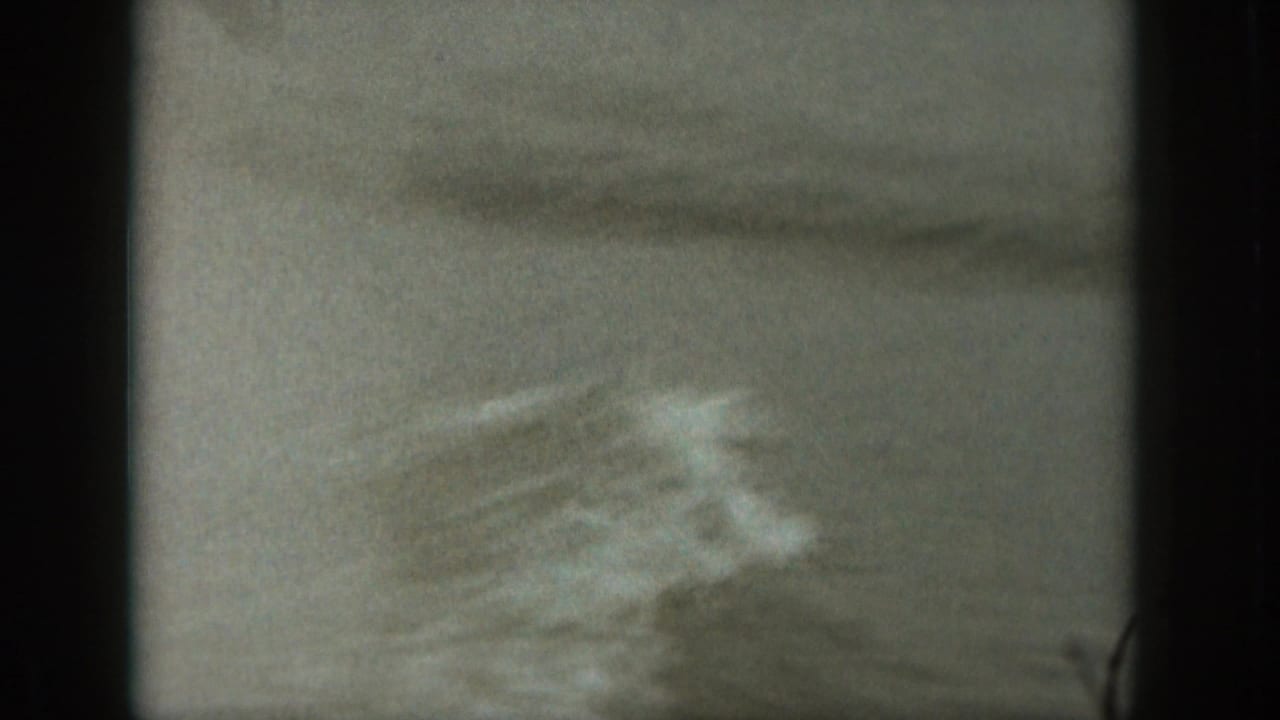 Soft 8mm frame of choppy Michigan water with a blurred patch of wake or spray crossing the surface.