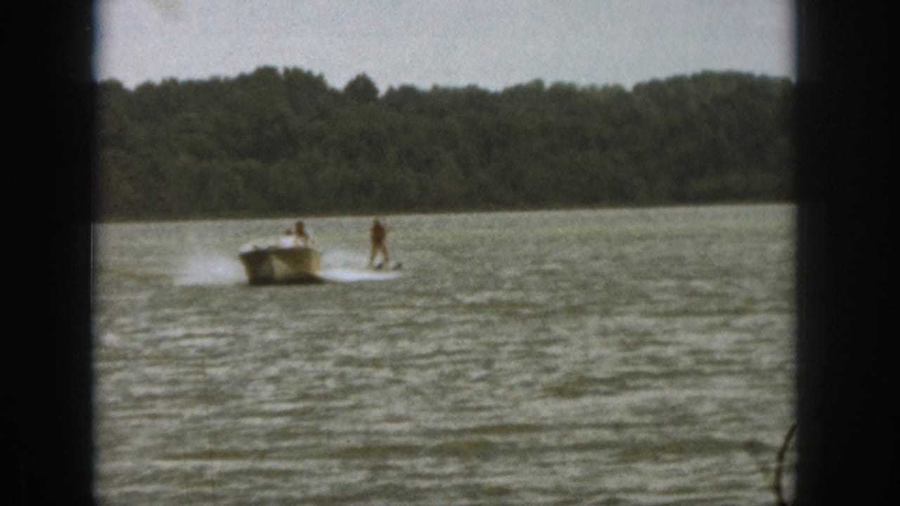 1961 Michigan lake footage shows one skier still upright behind a motorboat while another appears down in the water.