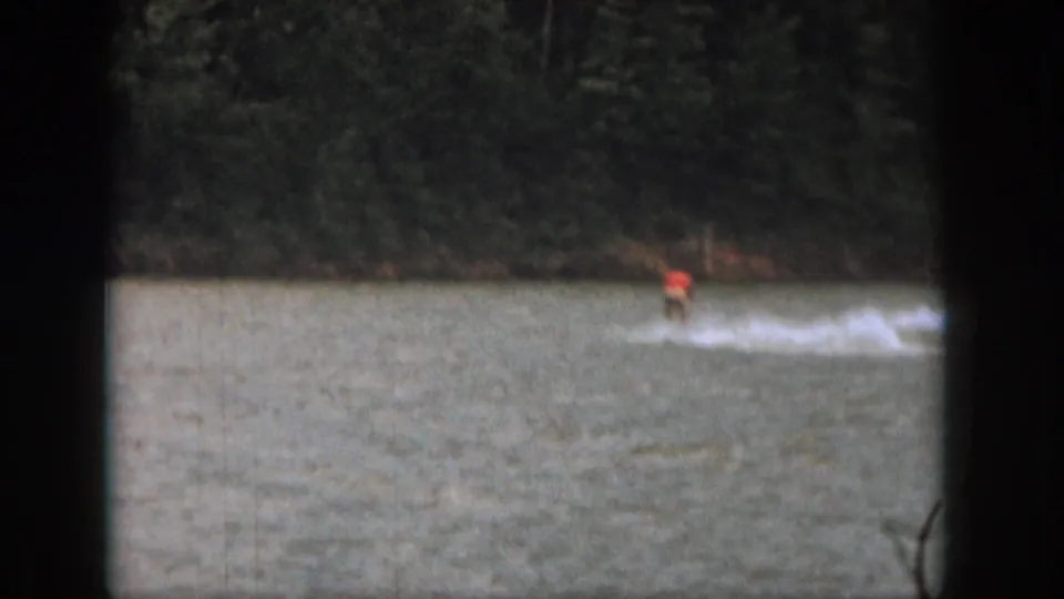 A distant water skier in a red top crosses the lake in this 1961 Michigan 8mm home-movie frame.