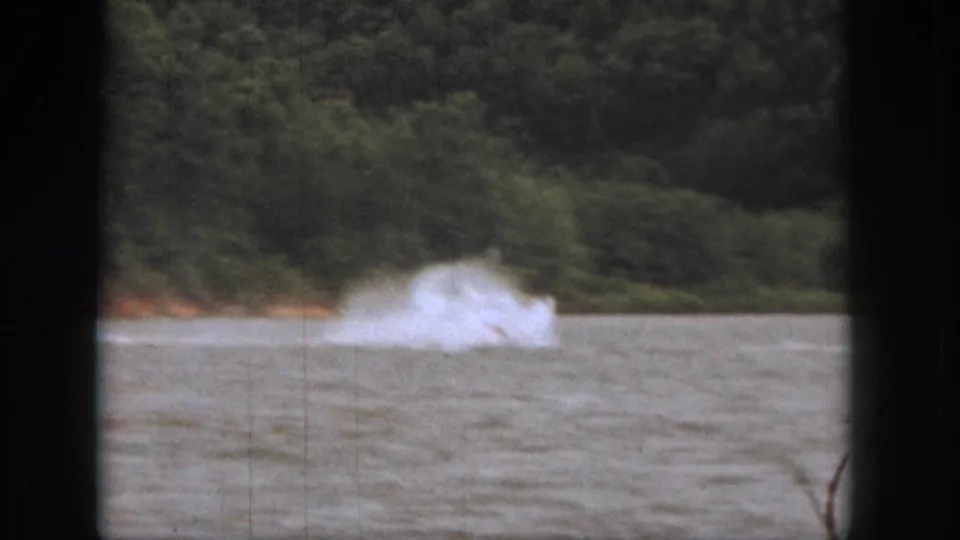 A large plume of spray marks the water skier's wipeout on a wooded Michigan lake in 1961 home-movie footage.