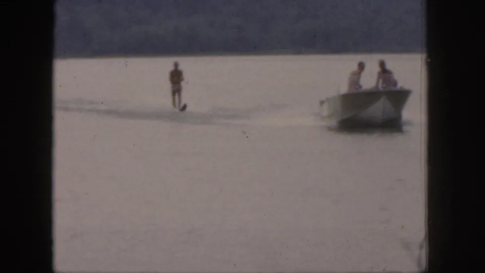 1961 Michigan 8mm frame with a water skier being towed behind a small motorboat carrying two visible occupants.