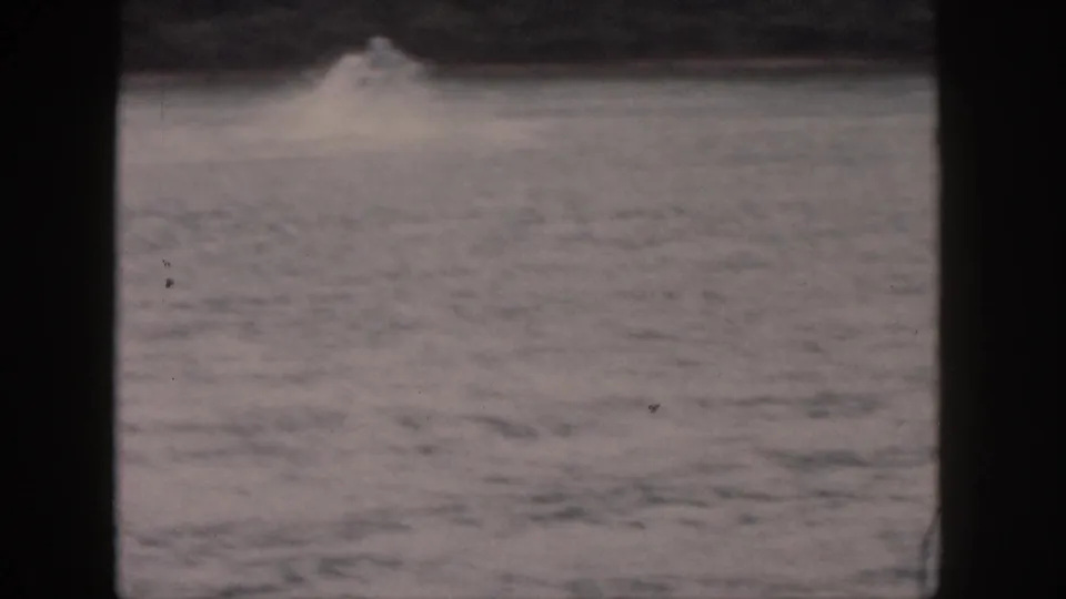 A splash rises on the Michigan lake after the water-skier falls, framed in soft 8mm home-movie color.