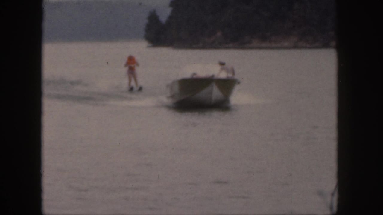 The final frame shows a small motorboat towing a standing water skier on a Michigan lake in vintage 8mm footage.