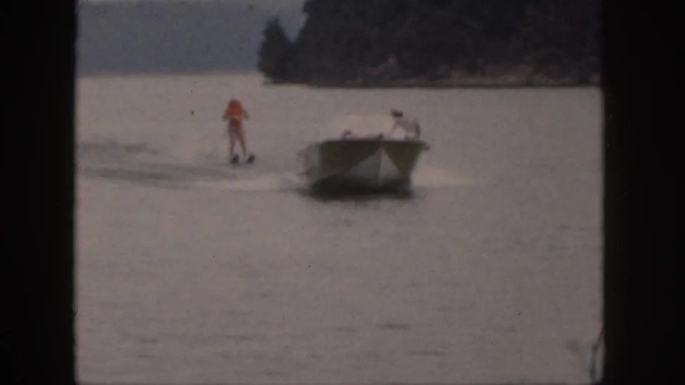 The final frame shows a small motorboat towing a standing water skier on a Michigan lake in vintage 8mm footage.