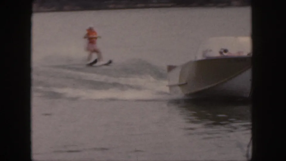 The skier rides near the motorboat wake, still upright but close to the churning water in this 1961 Michigan lake scene.