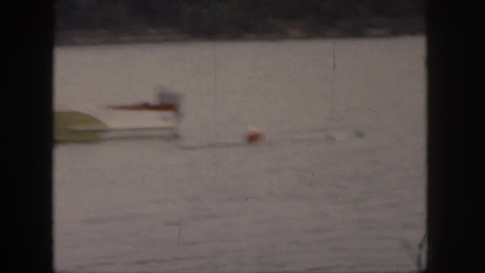 Soft 1961 Michigan lake frame with a small motorboat moving across the water and a colored float nearby.