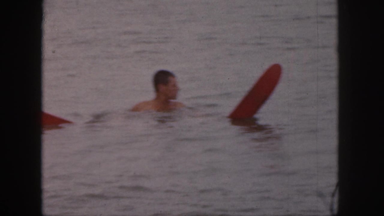 Man in water turning near an upright red board.