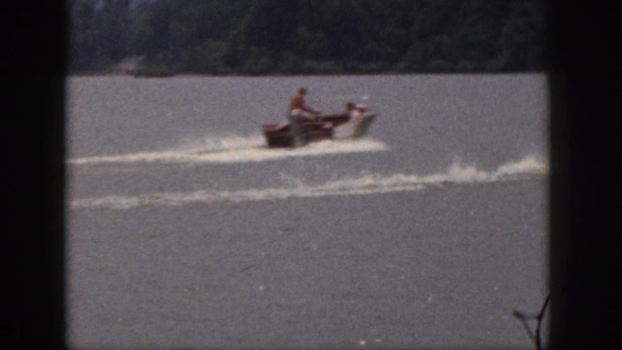 Small motorboat crosses the lake, leaving a pale wake behind it.