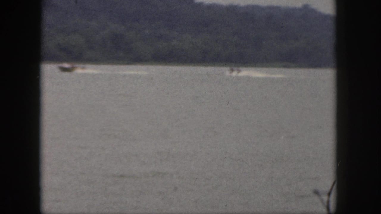 Wide lake view with a small distant boat near a wooded shoreline.
