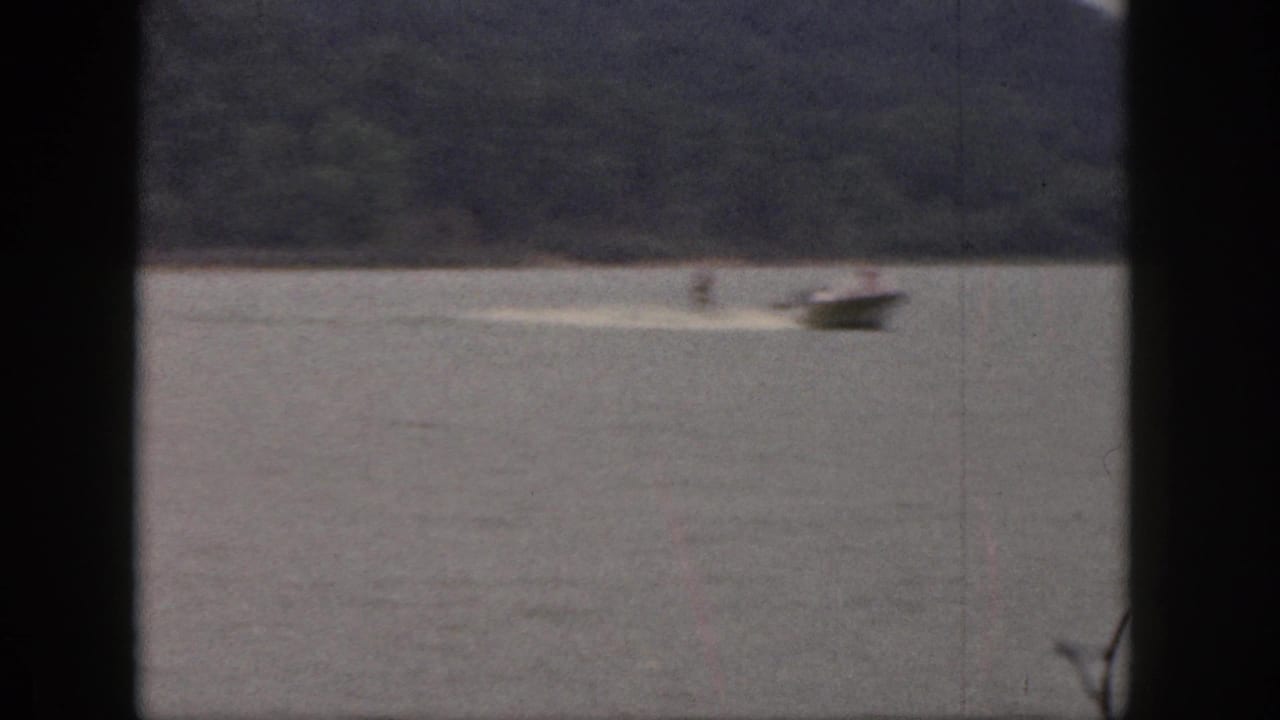 Speedboat pulls a distant skier across open lake water.