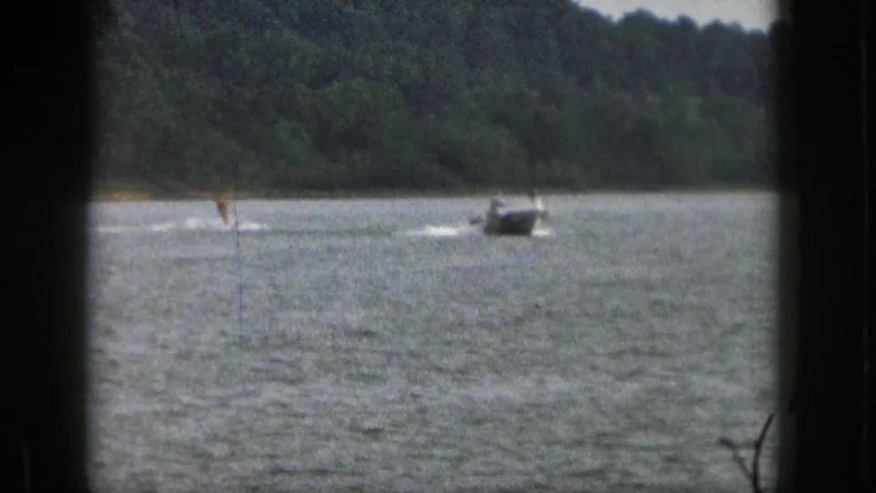 1961 Michigan 8mm frame showing the skier and motorboat farther across the lake, with dark frame edges and visible grain.