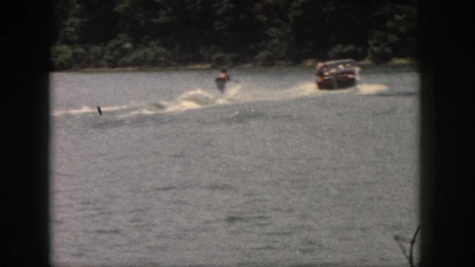 The boat and skier move across the lake in a soft, grainy 1961 Michigan home-movie frame.
