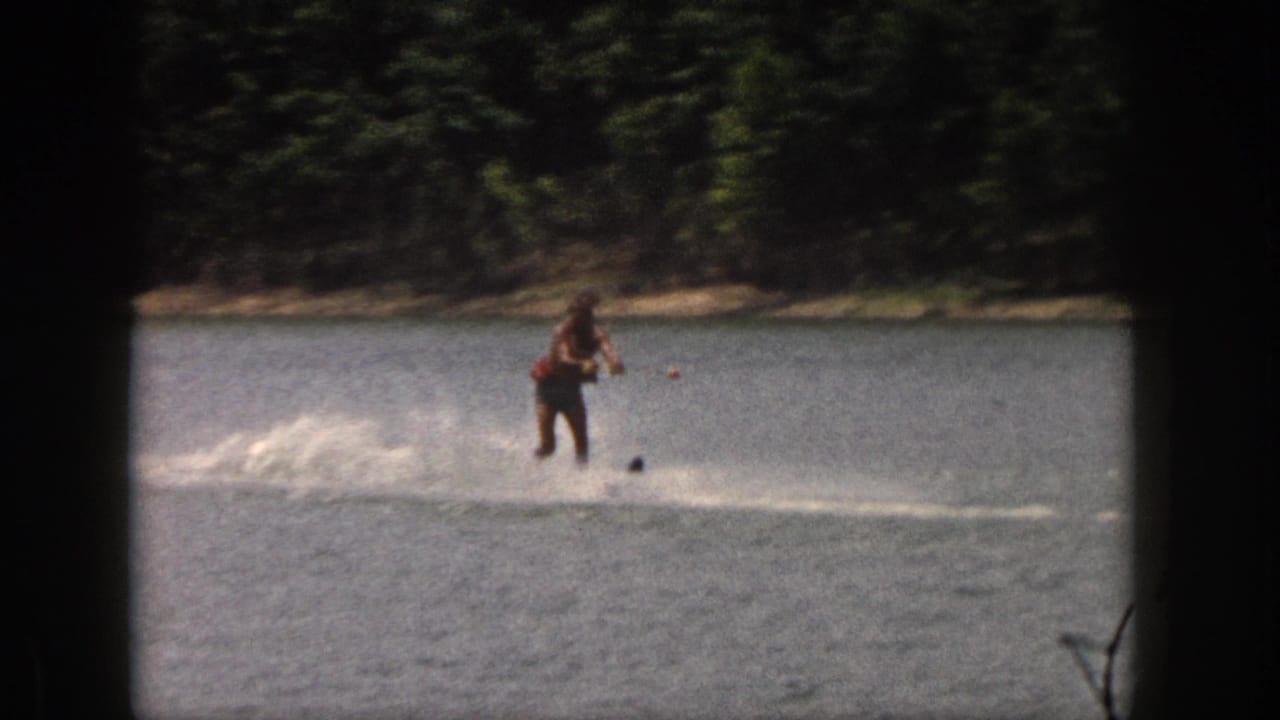 Water skier rides across open water with spray behind them.