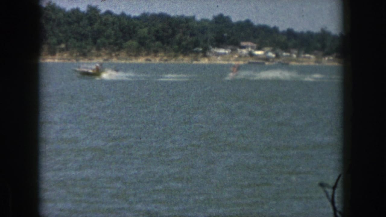 Boat and distant water skier crossing the lake with wakes behind them.