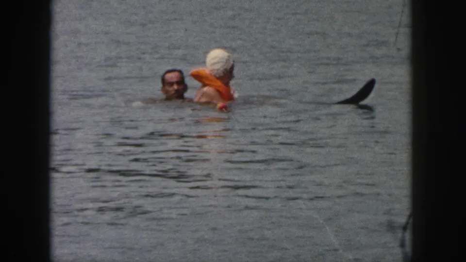1961 Michigan 8mm frame showing a man and woman facing each other while swimming in open lake water.