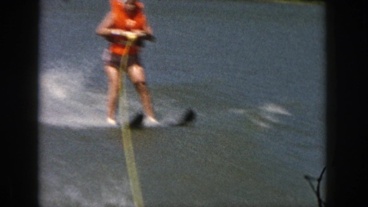 Water skier holding a yellow tow rope while moving across the lake.