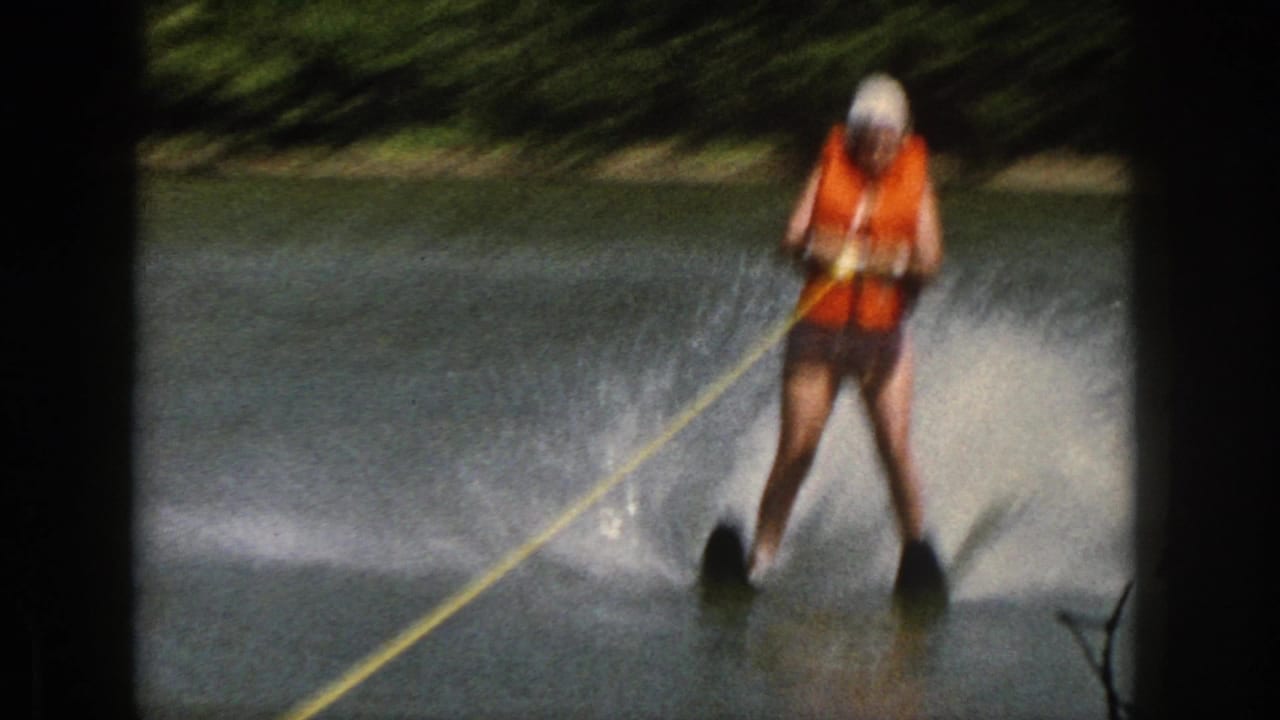 Water skier holding a yellow tow rope while crossing the river.