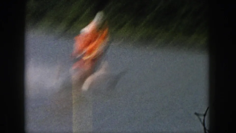 1961 Michigan 8mm frame with a motion-blurred skier in an orange life vest crossing the lake on water skis.