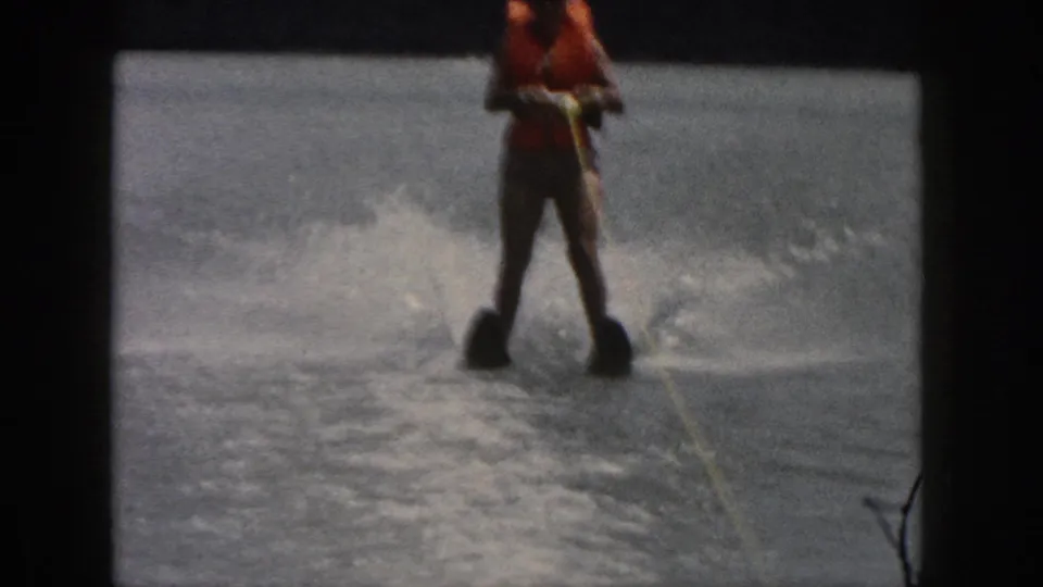 1961 Michigan 8mm frame with a closer view of the skier, orange life jacket, tow rope, and splashing water.