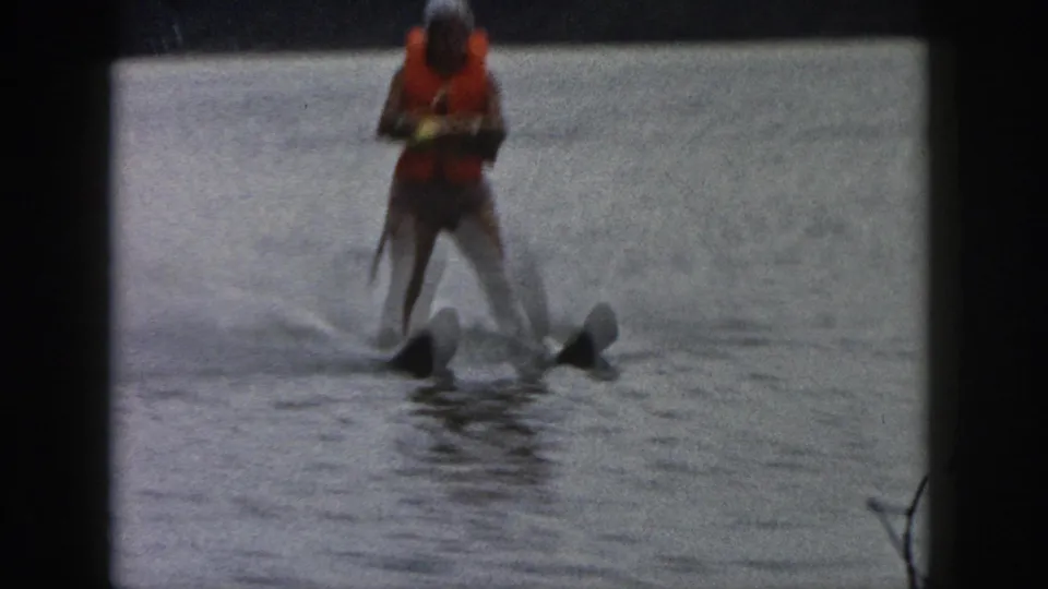 1961 Michigan 8mm frame showing the skier cutting through the water as spray rises around the skis.