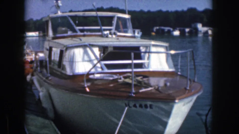 Close 1961 Michigan frame showing the bow, cabin windows, railings, and registration marking on a docked classic motorboat.