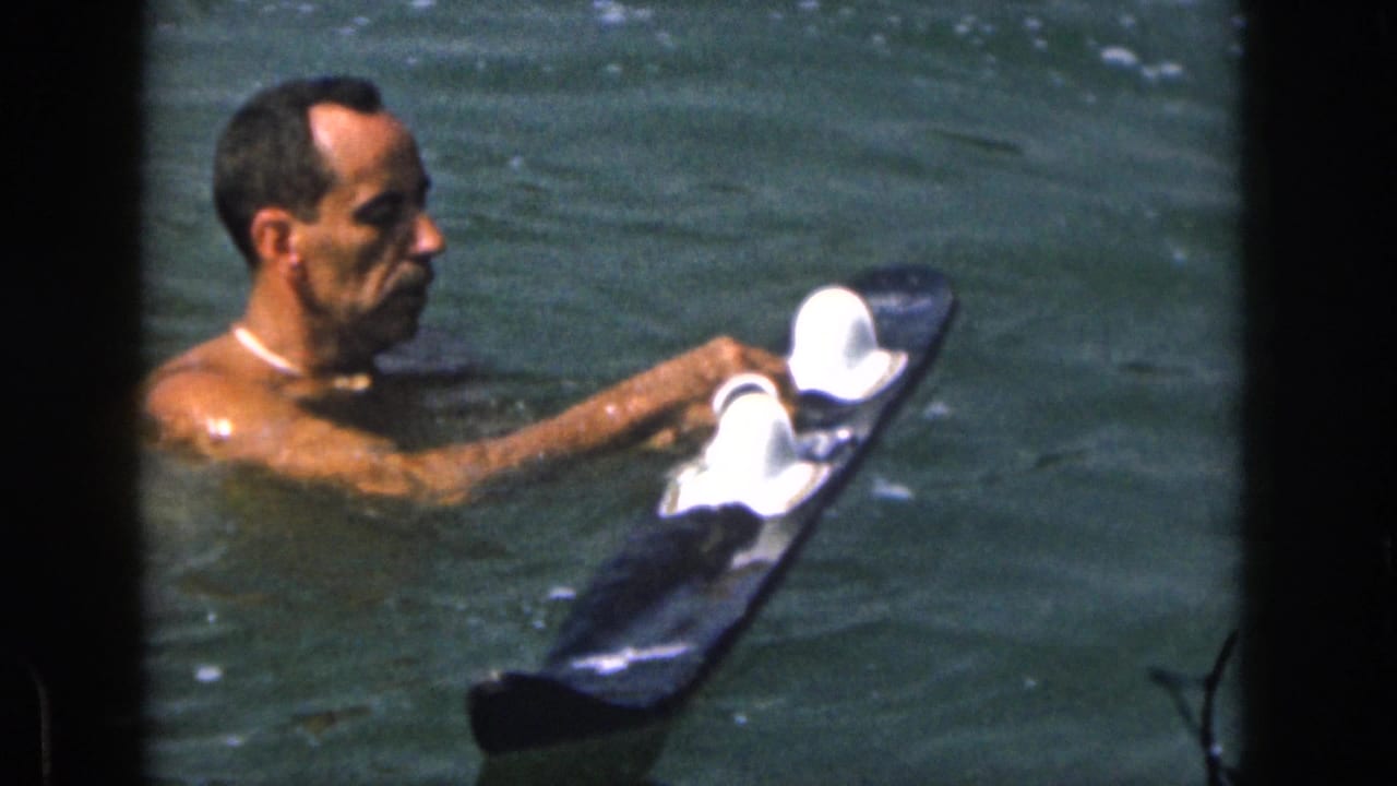 Man adjusts white-topped water skis while floating in the lake.