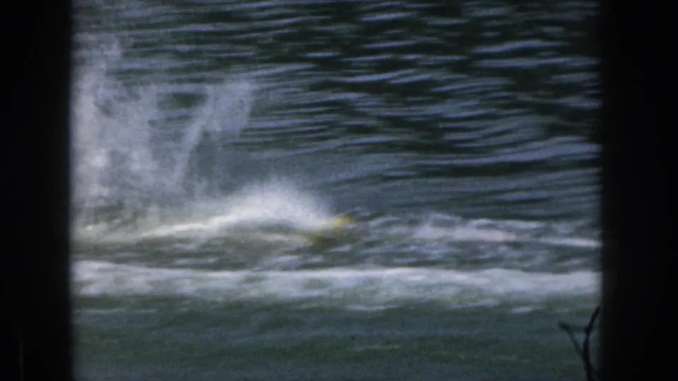 A distant skier appears to hit the water or turn sharply, throwing up spray on a Michigan lake in 1961.