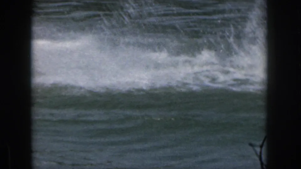1961 Michigan 8mm frame showing choppy lake water, white wake, and dark scan borders with no clear person in view.