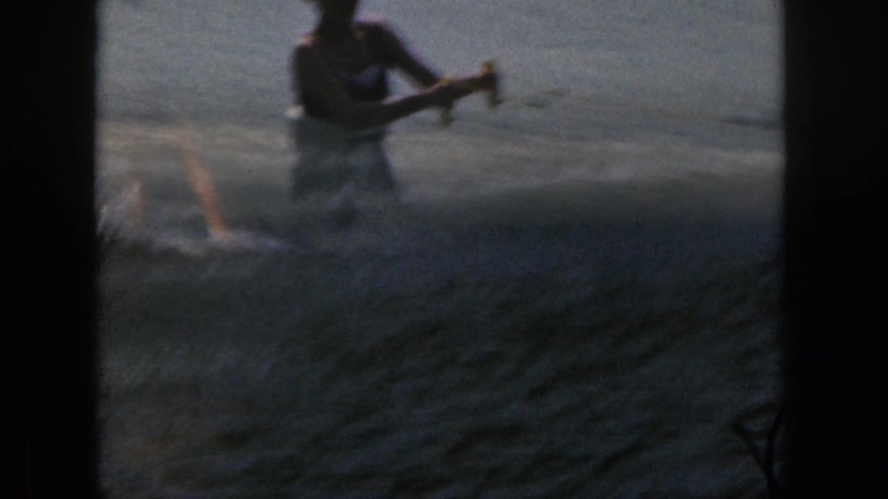 Water skier near the top of the frame as spray rises on the lake.