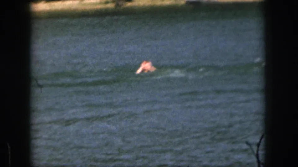 After the fall, the skier appears as a small figure in the lake, with rippled water filling most of the frame.