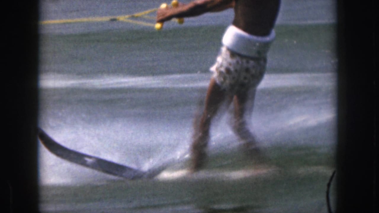 Close view of a man water skiing through spray while holding a tow rope.