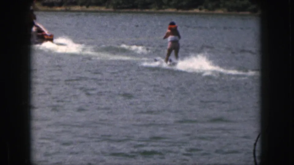 1961 Michigan 8mm frame showing a water skier behind a motorboat, with strong spray and lake surface visible.