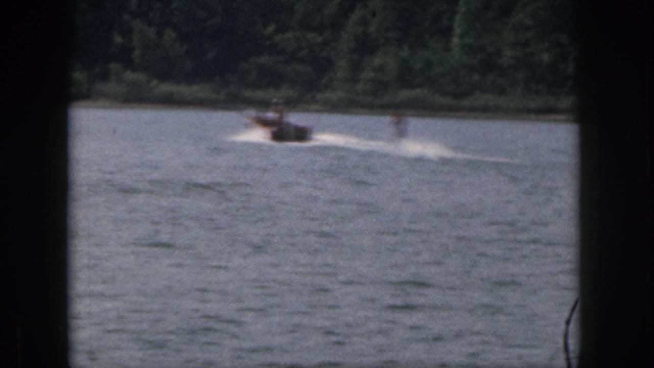 Small motorboat moves across lake water with a wake behind it.