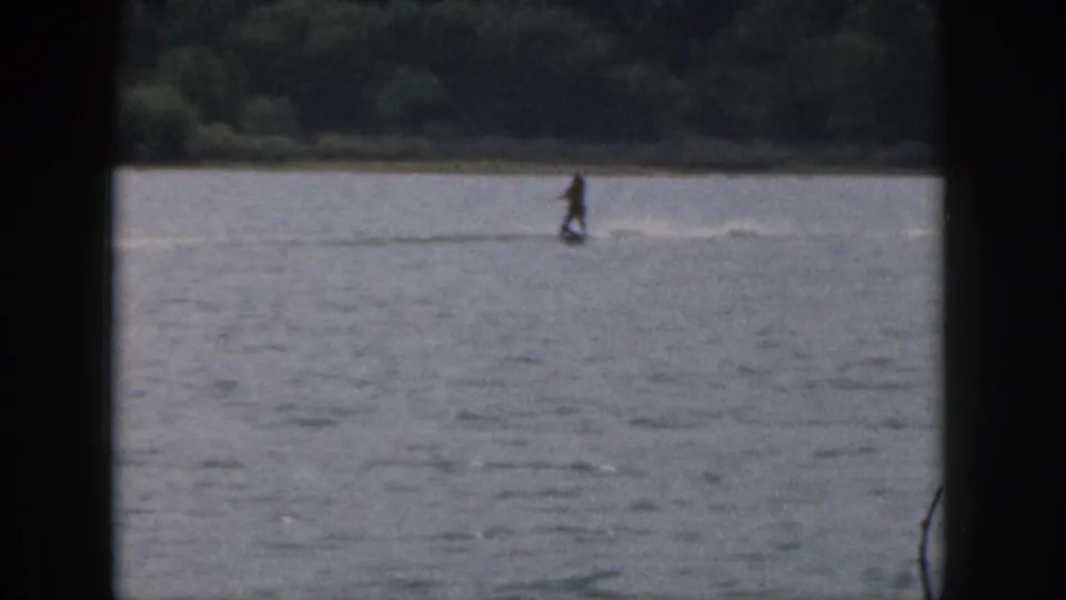 1961 Michigan resort-lake footage with a skier upright on the water, seen from a distant home-movie viewpoint.