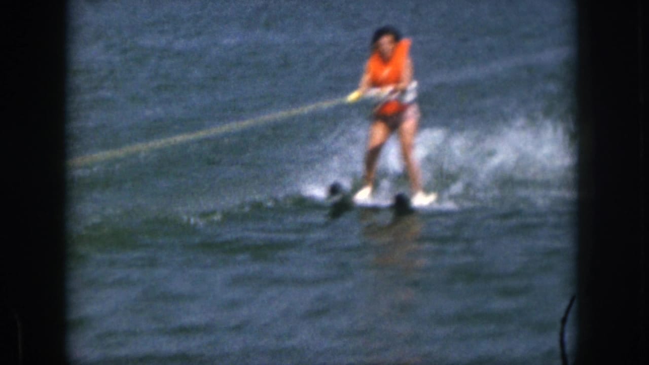 Woman on water skis glides across the lake with spray behind her.